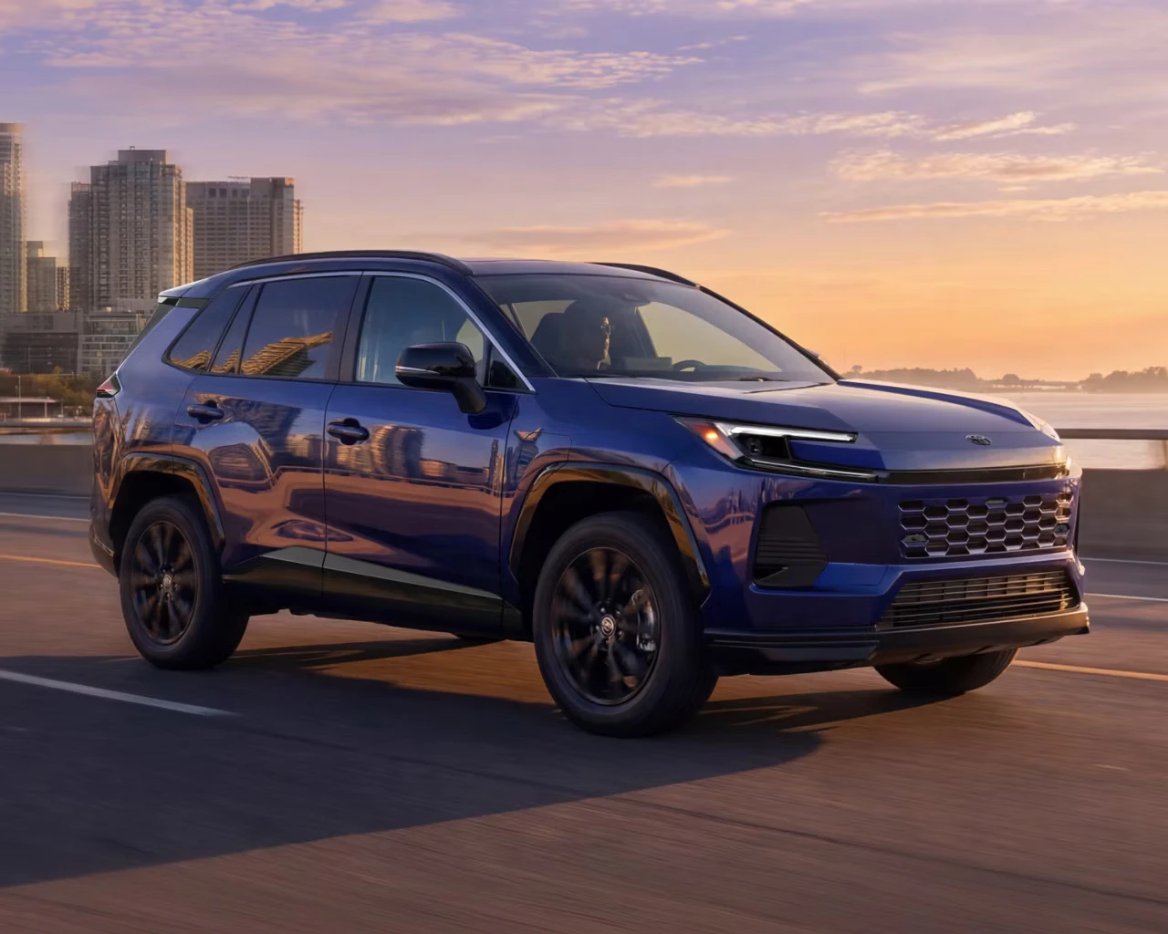 Toyota 2026 RAV4 Plug-In Hybrid driving in the city at sunset
