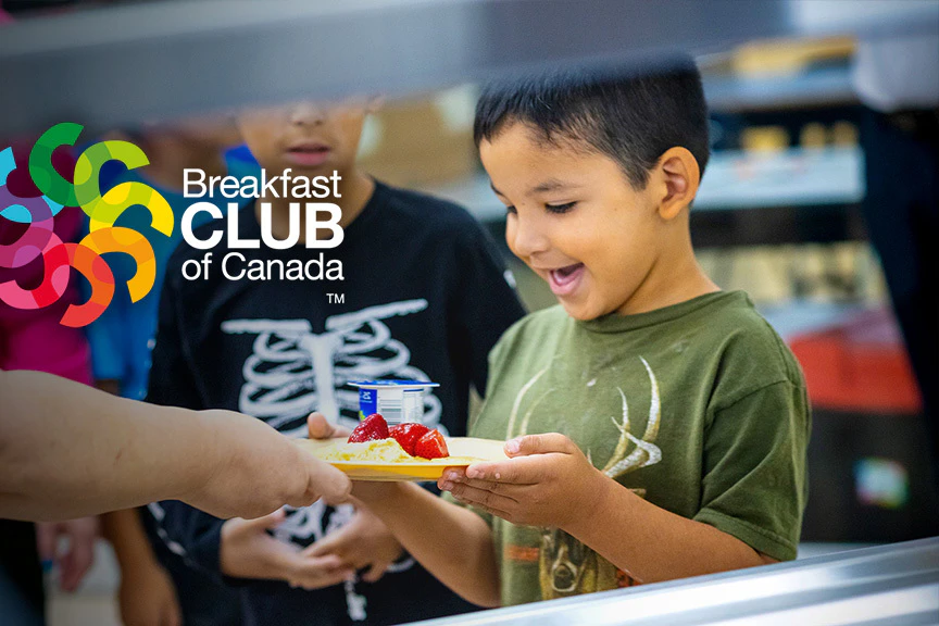 Child receiving breakfast plate with Breakfast Club of Canada logo