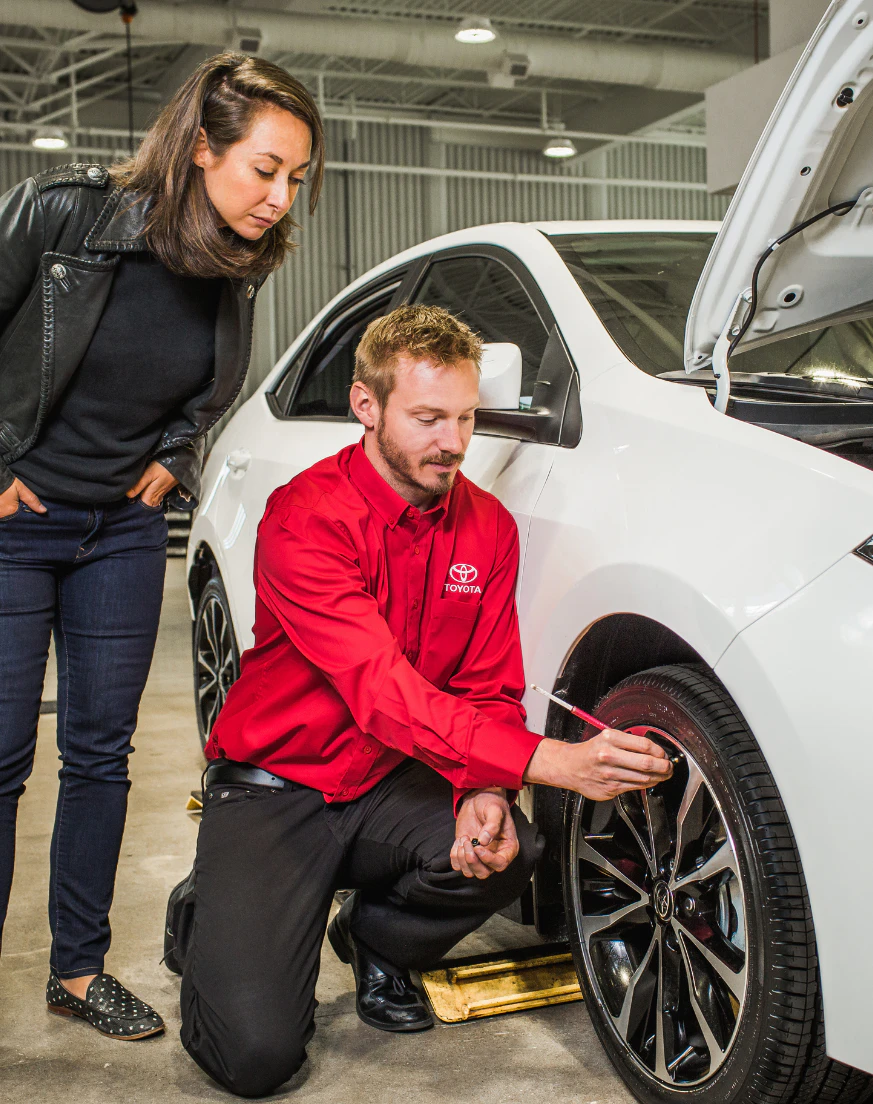 Toyota service technician inspecting tire condition with customer in service bay