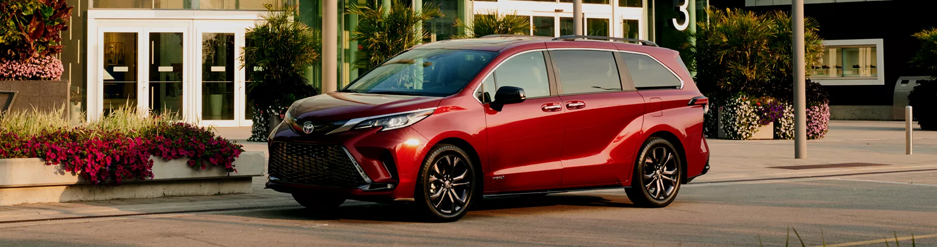 A Toyota Sienna parked in front of an entrance with flowers