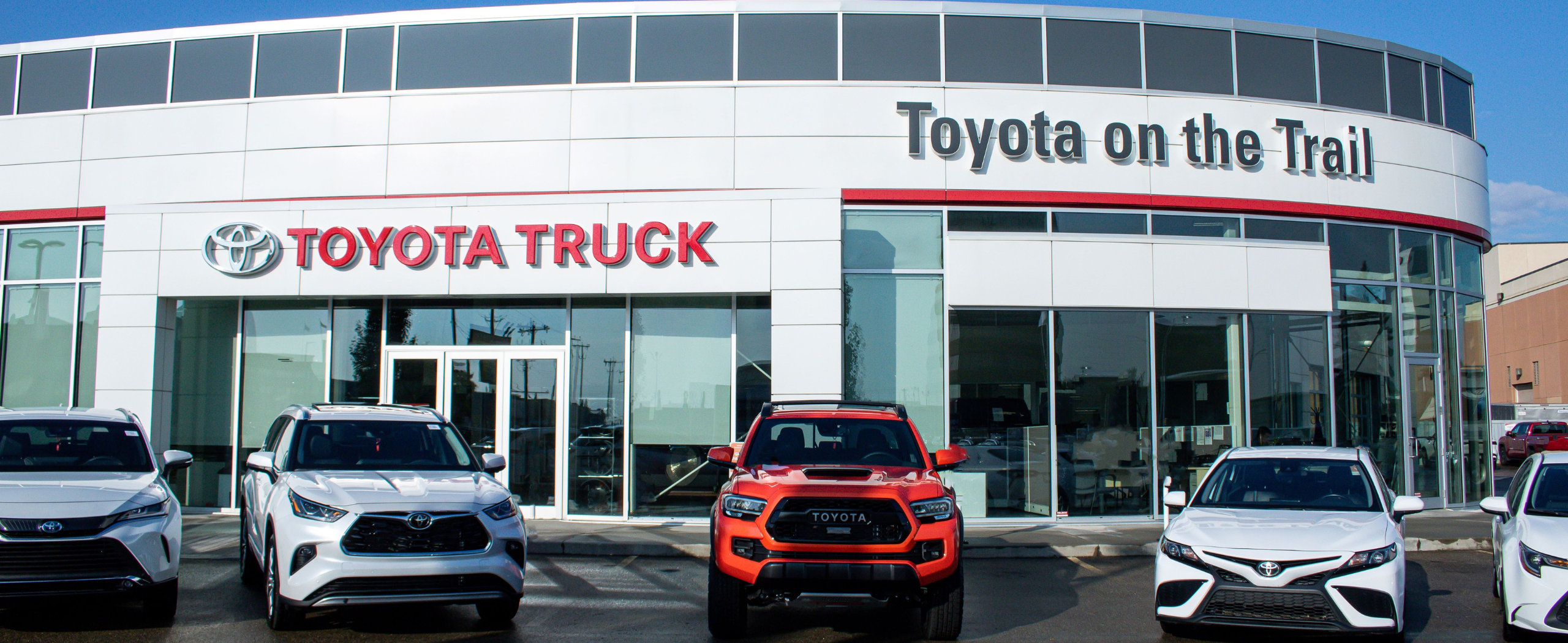 The outside of Toyota on the Trail car dealership in Edmonton. It has multiple Toyotas parked in front of it.