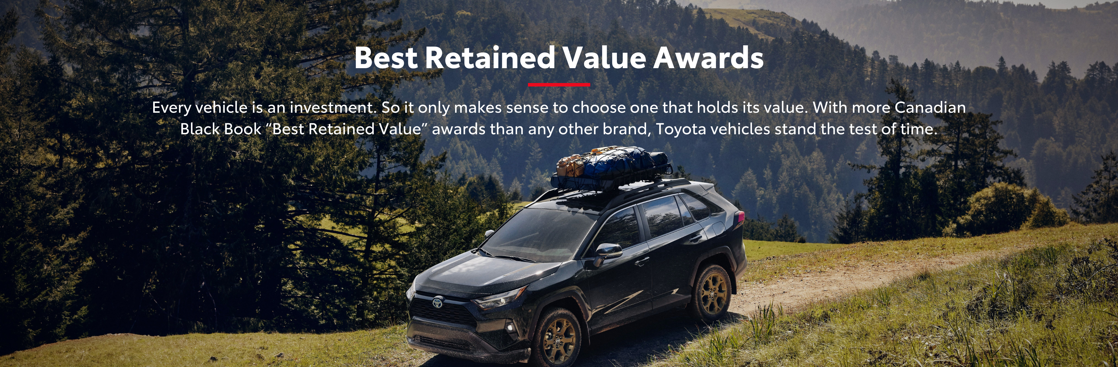 An image of a Toyota on top of a mountain or hill with lots of trees in the back