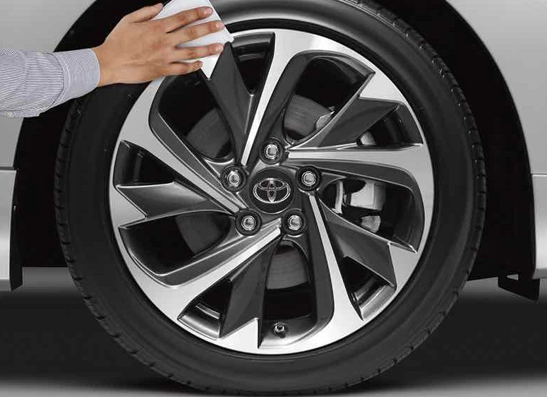 Close up of a car wheel and someone wiping the rims.