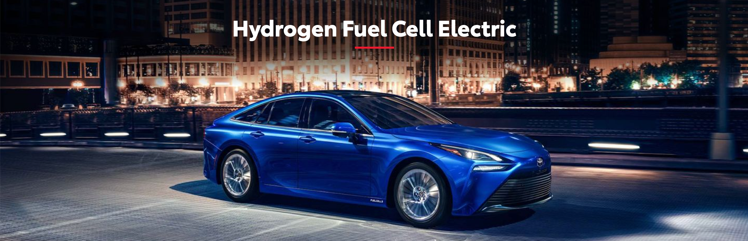 a hydrogen fuel cell electric Toyota parked in a city at night.