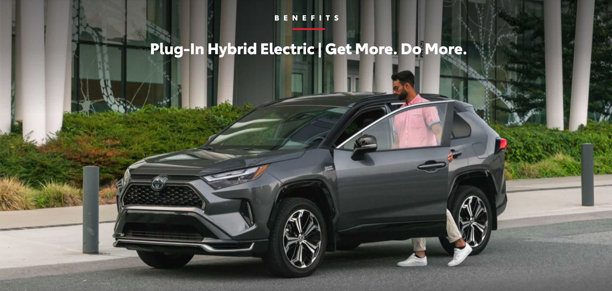 A man in a pink shirt getting into his plug-in hybrid electric Toyota.