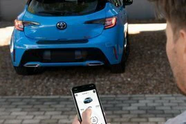 a person standing in front of a blue Toyota using Remote Connect