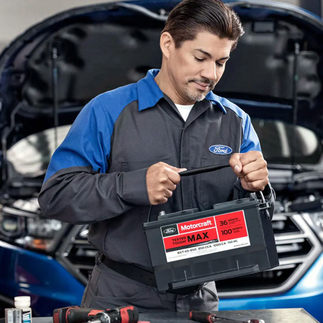 Ford service technician holding Motorcraft battery in service bay