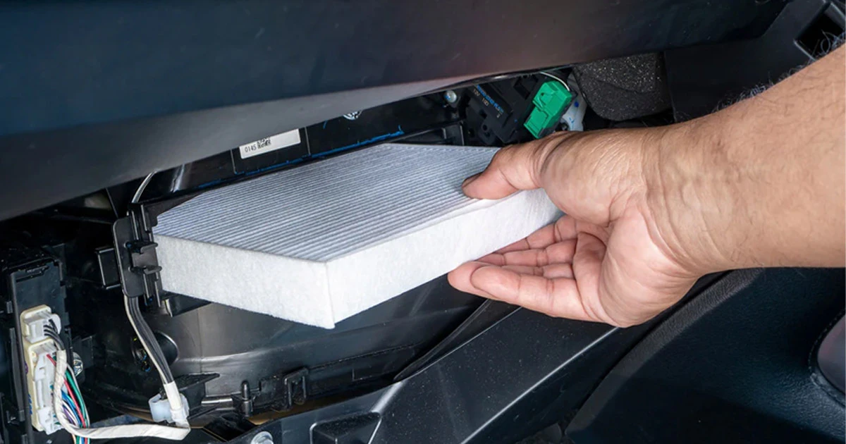 Technician holding Ford cabin air filter during replacement service
