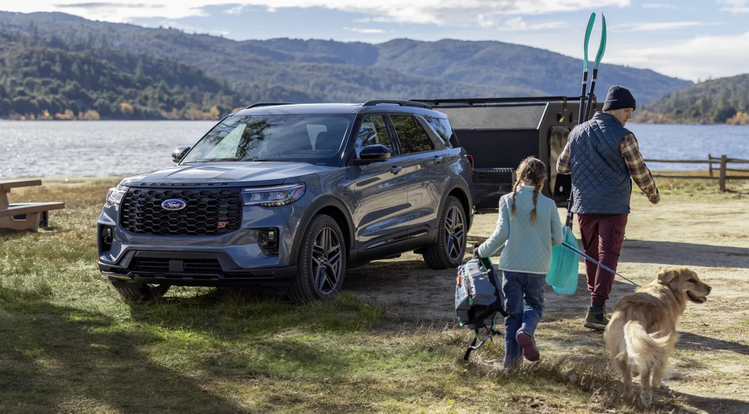Ford SUV parked at lake with family and dogs loading recreational gear into open cargo area