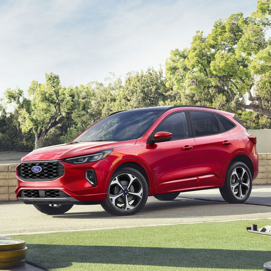 2026 Ford Escape red compact SUV parked in driveway with trees in background