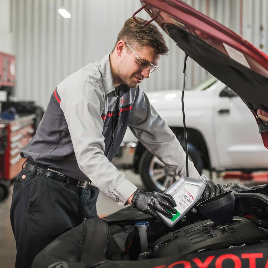 Service technician performing oil change on Toyota vehicle in service bay