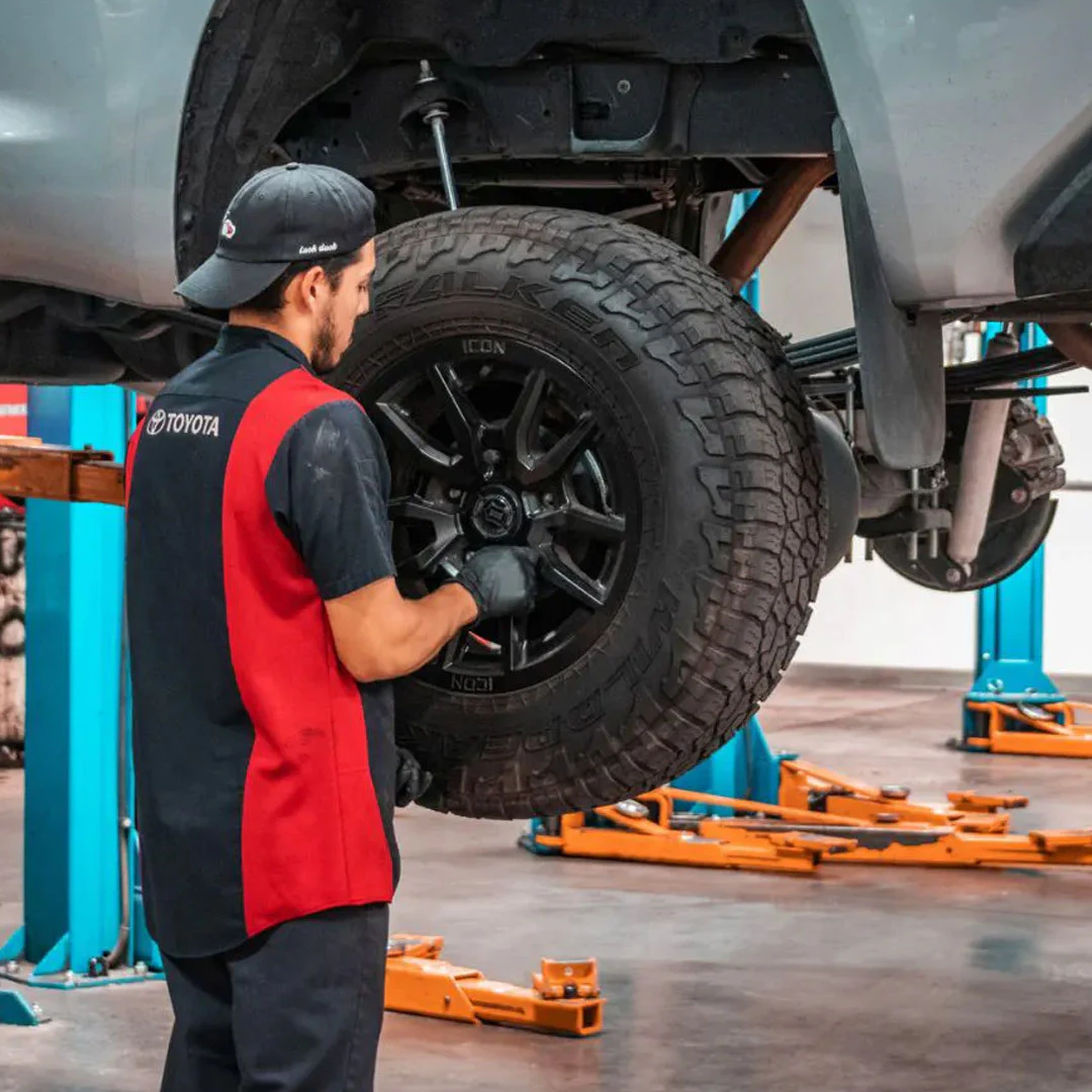 Service technician removing a tire during wheel alignment on a Toyota vehicle