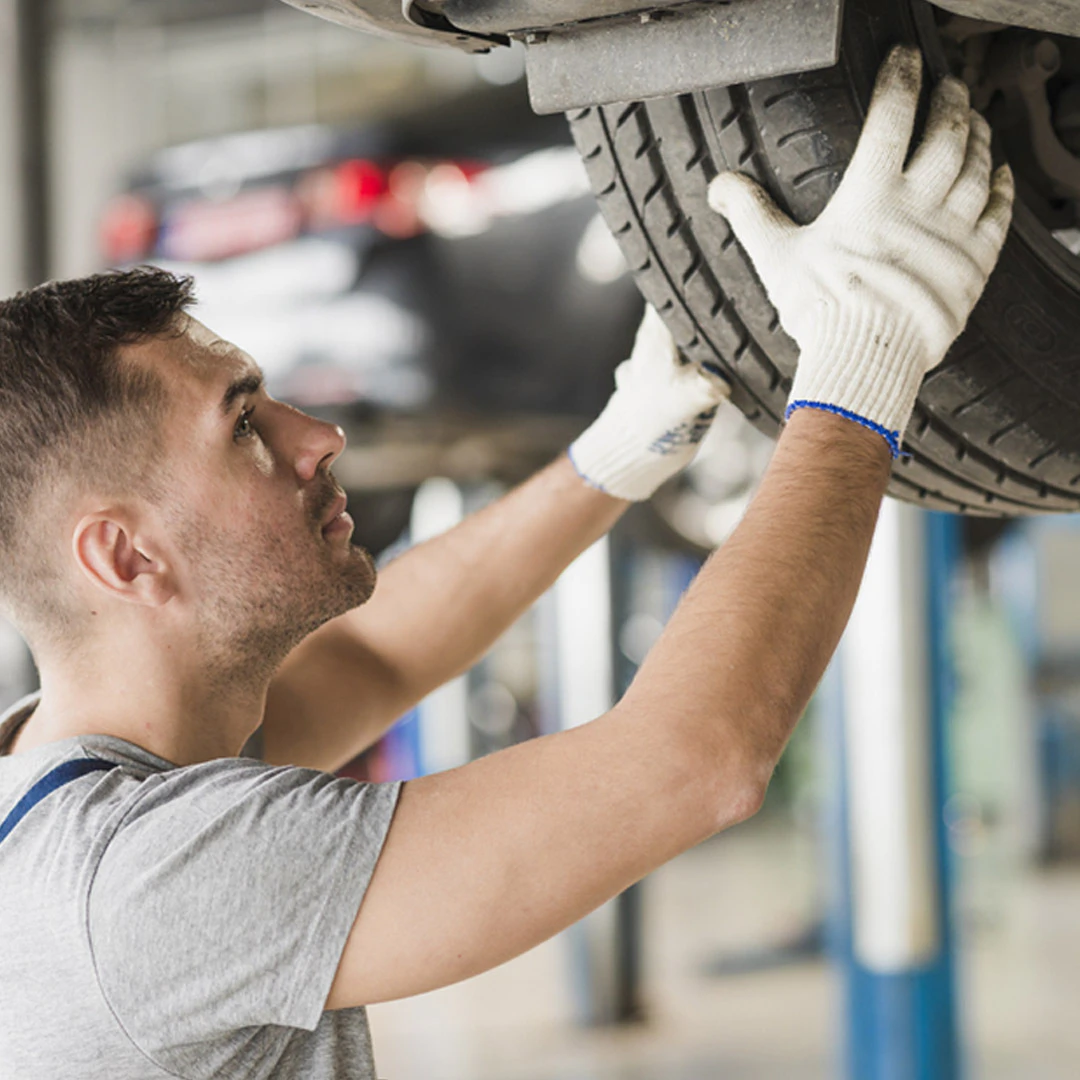 Service technician inspecting a tire during maintenance in a workshop