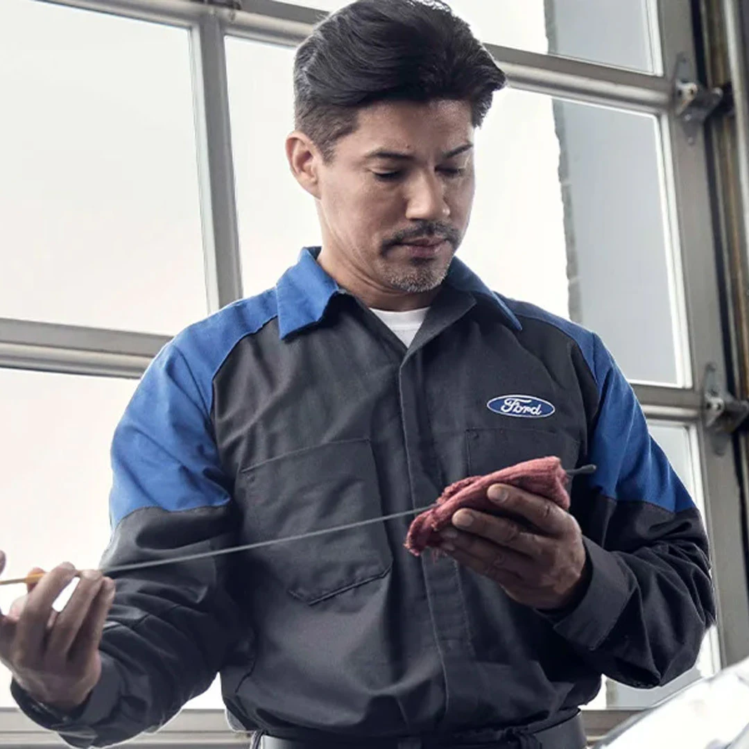 Ford service technician checking oil level during maintenance in Edmonton