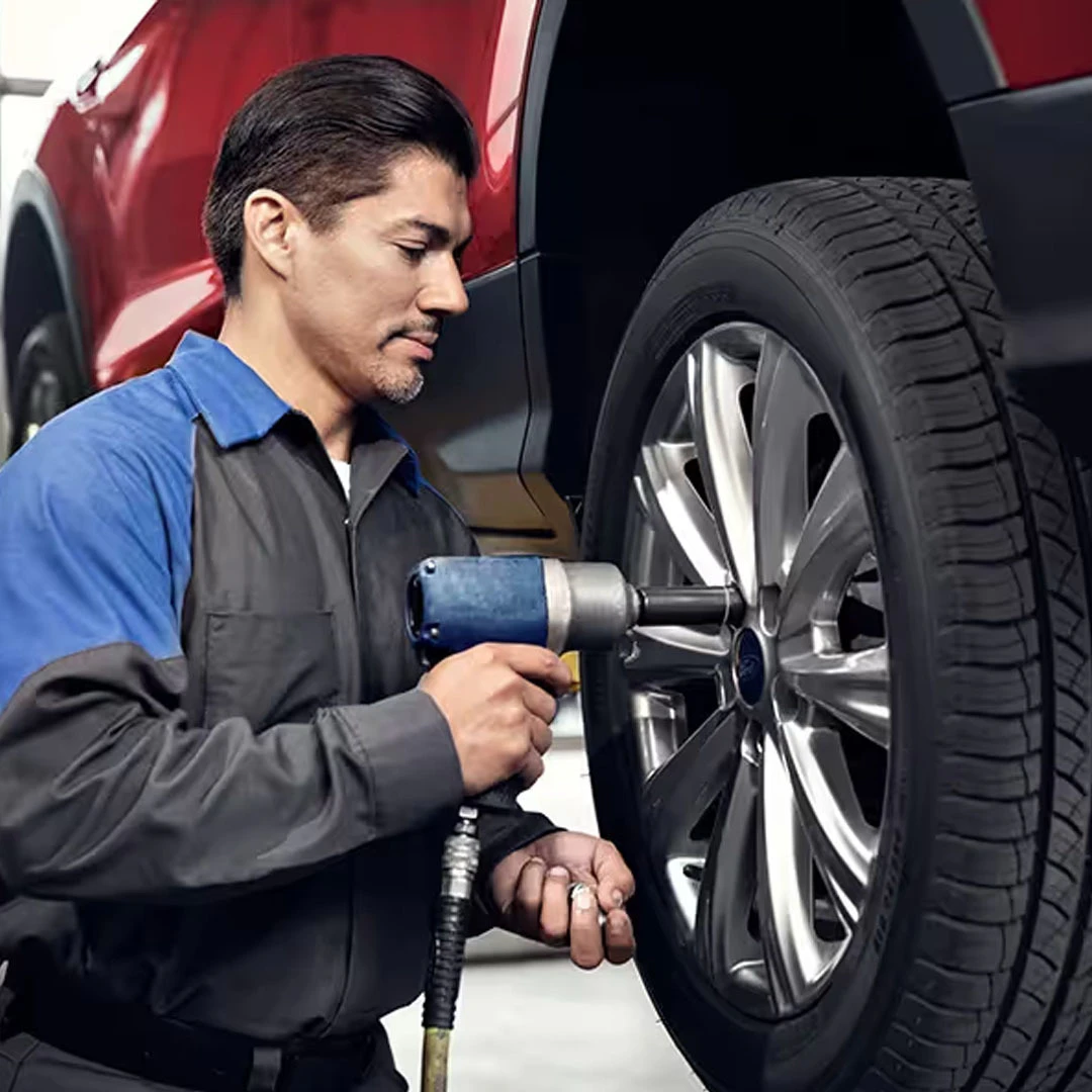 Service technician removing a lug nut with an impact wrench during tire service on a Ford vehicle