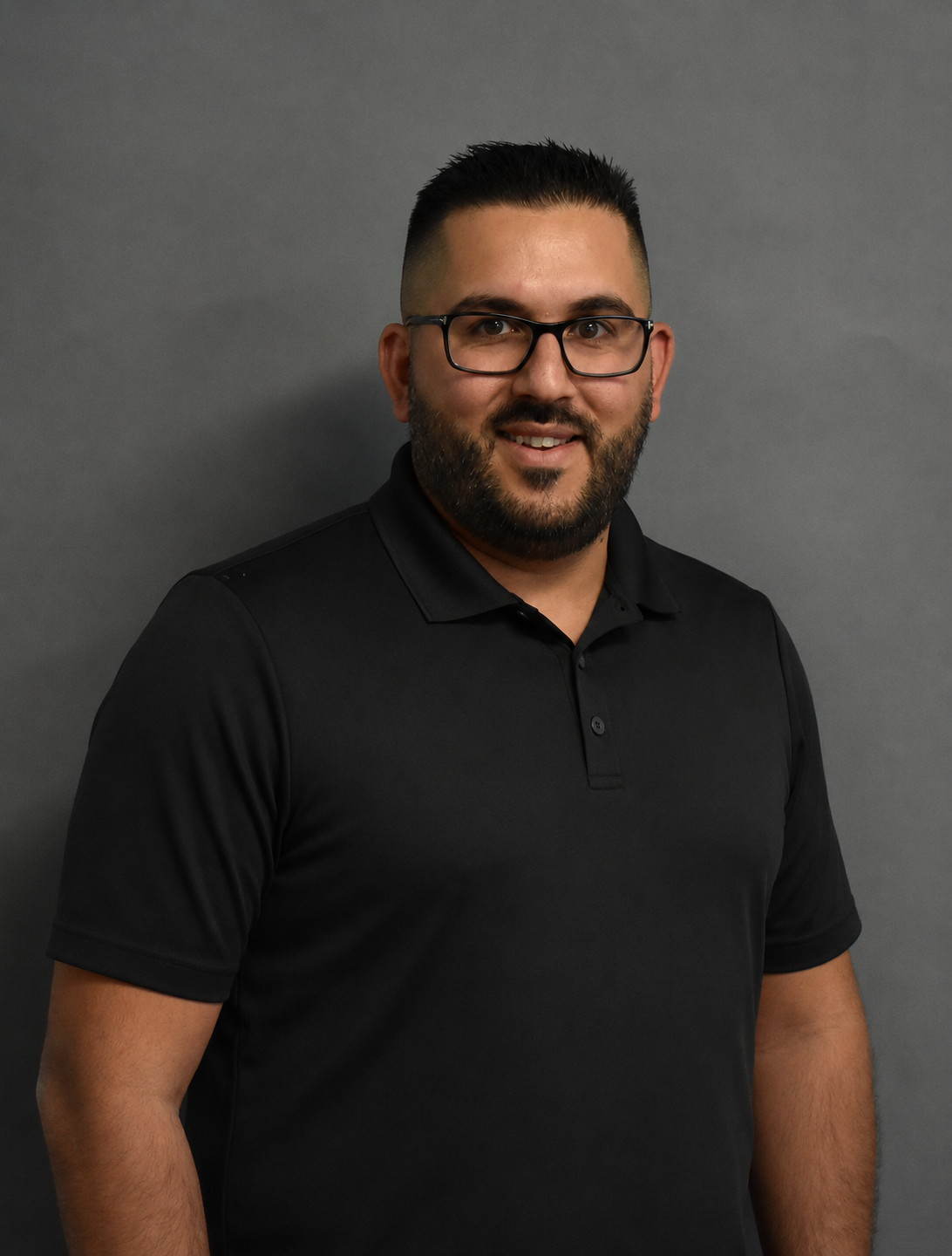 Go Auto sales team member smiling wearing black polo shirt and glasses
